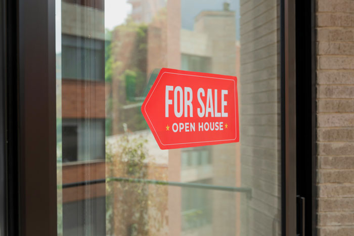 Red For Sale open house sign on glass door, representing oldschool home trends millennials are over.