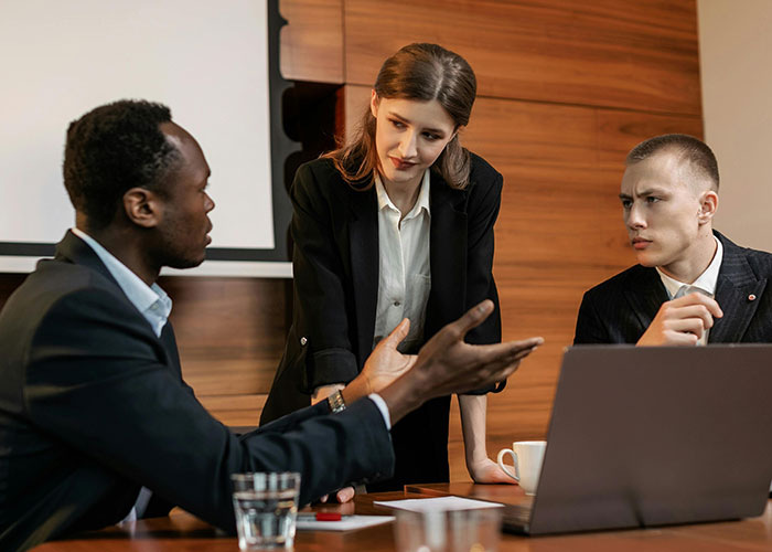 Three employees in a formal meeting with concerned expressions, illustrating micromanagement in the workplace.