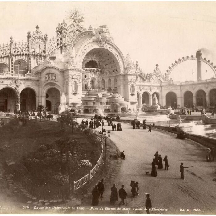 Victorian era old architecture with detailed arches, fountains, and people strolling in a historic public park setting.