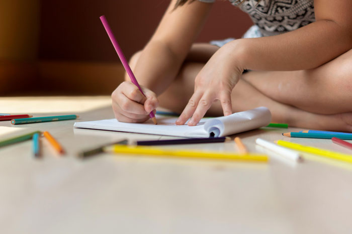 Child drawing with colorful pencils on floor, illustrating therapists share differences between men and women concept. - 18