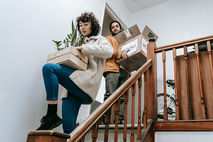 Woman and man carrying boxes down stairs, illustrating a woman who doesn't share important news with dad after last attempt
