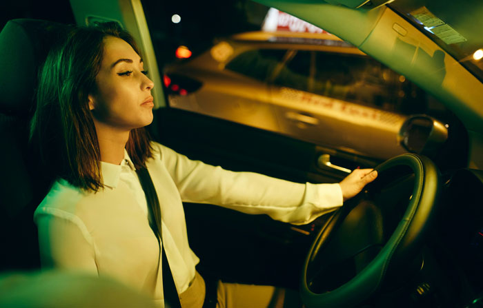 Young woman driving at night, focused and alert, demonstrating tips to stay safe and alive while behind the wheel.