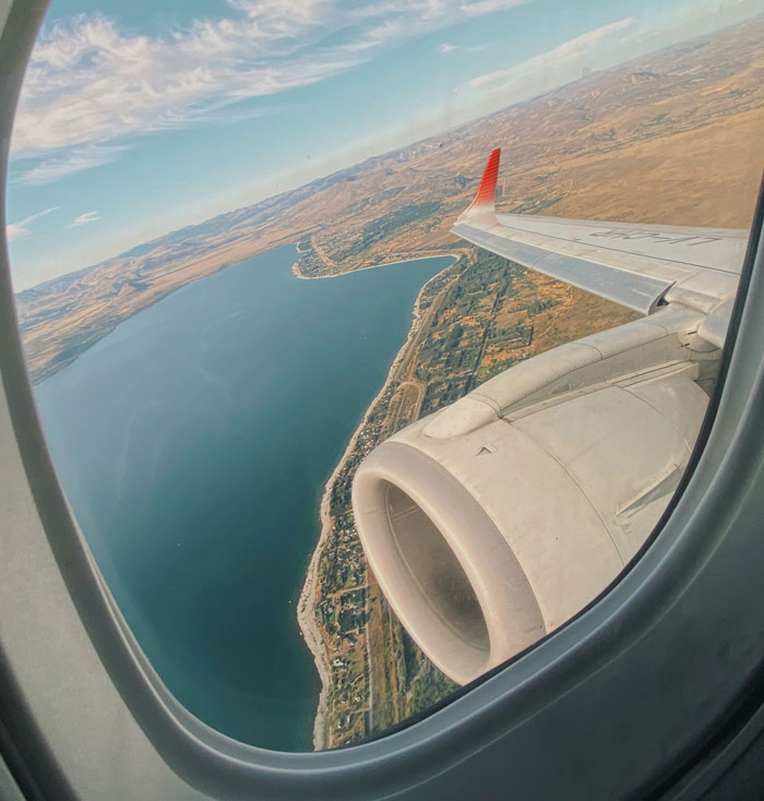 View of landscape and coastline from airplane window showing wing and engine during flight about the rich lifestyle