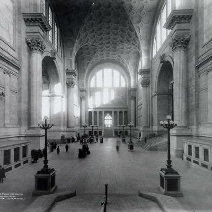 Spacious hall featuring old architecture with tall columns, arched windows, and intricate ceiling details showcasing historical design.