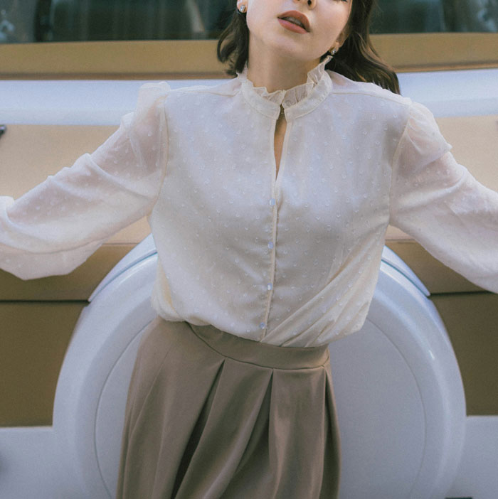 Woman in a white blouse and beige skirt posing with a washing machine, related to unexpected things learned about the rich.