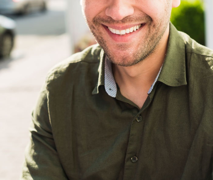 Smiling man in a green shirt outdoors representing men in public spaces related to inappropriate comments shared by women.