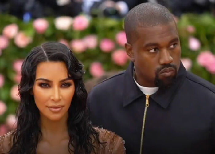 Kim Kardashian and Kanye West posing at a formal event with floral background related to KarJenner clan controversies. - 6