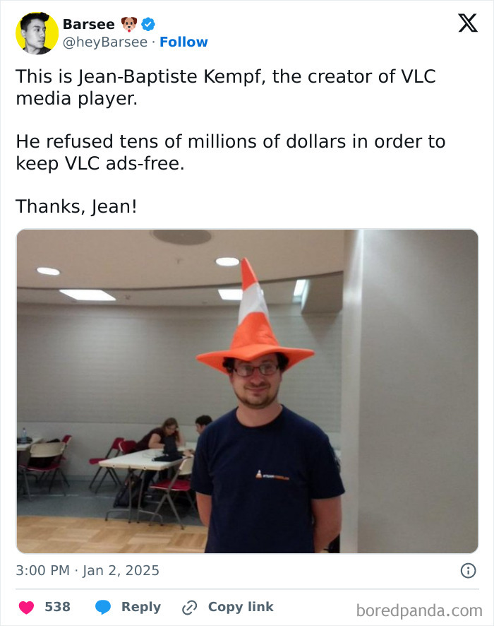 Man wearing orange cone hat and dark shirt indoors, symbolizing the beauty of planet Earth and technology innovation.