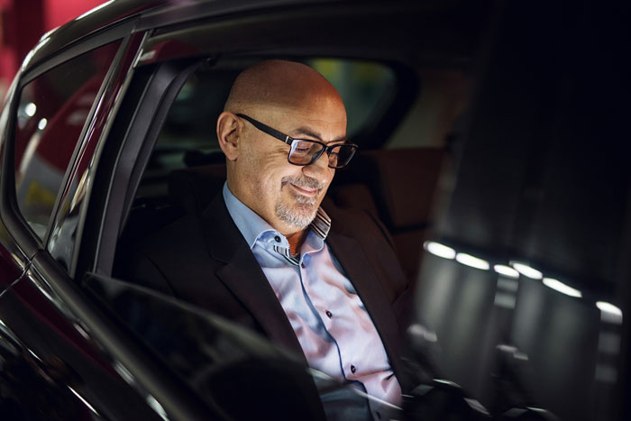 Man in glasses and suit sitting in a car, representing unexpected things people learned about the rich after interaction