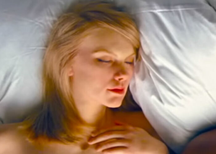 Blonde woman lying in bed with eyes closed, resting on white pillows, representing KarJenner clan controversies. - 26