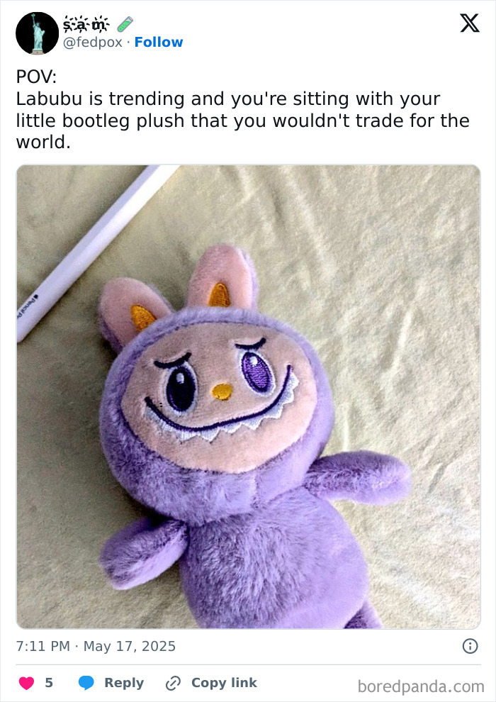 Plush Labubu doll with a quirky smile and bunny ears lying on a beige fabric surface, trending online.