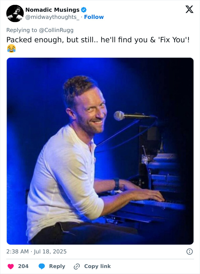 Chris Martin playing piano on stage with a microphone in front during a Coldplay concert with blue lighting.