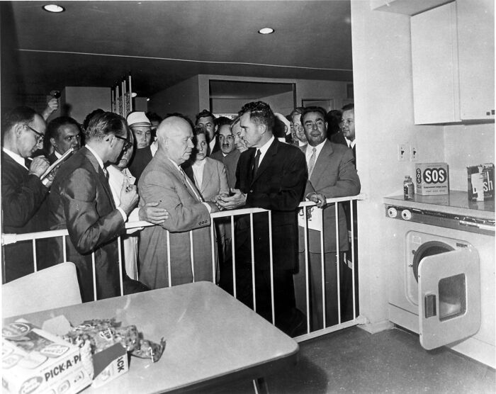 Rare and interesting historical photograph showing a group of men gathered around a washer and dryer in a kitchen setting.