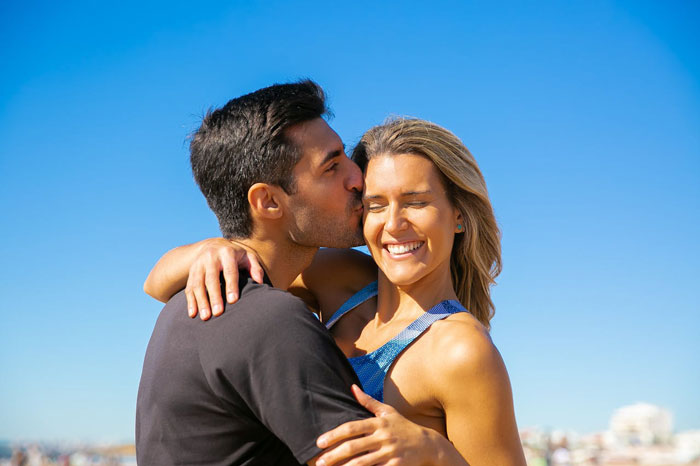 Couple embracing outdoors on a sunny day, highlighting themes of jealousy and spying in a husband’s work life.