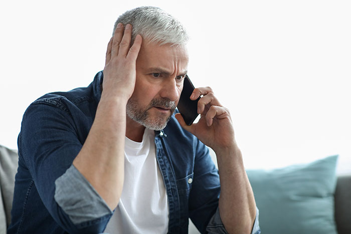 Middle-aged man with gray hair and beard looks worried while talking on phone, dealing with babysitting emergency refusal - 10