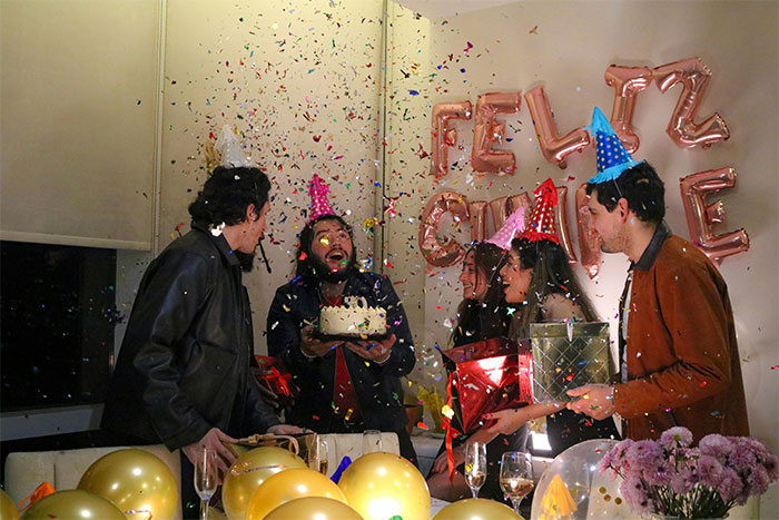 Group celebrating a surprise birthday party with confetti and gifts, highlighting guy’s female best friend and girlfriend dynamics. - 1