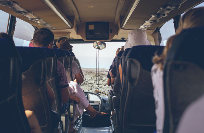 Tourists seated inside a tour bus on a rocky landscape, highlighting a guide-led travel experience. - 5
