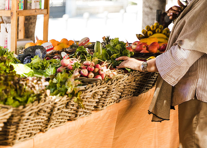 Person picking fresh produce at a farm stand with various vegetables, highlighting issues with a neighbor's farm stand.