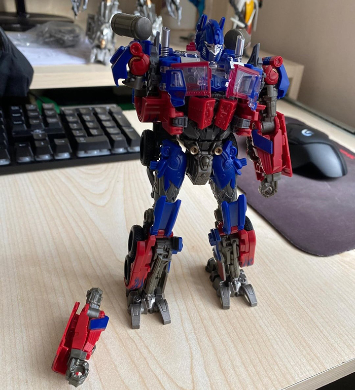 Toy robot standing on a desk with a broken arm next to it, related to upset woman and broken sentimental toy.