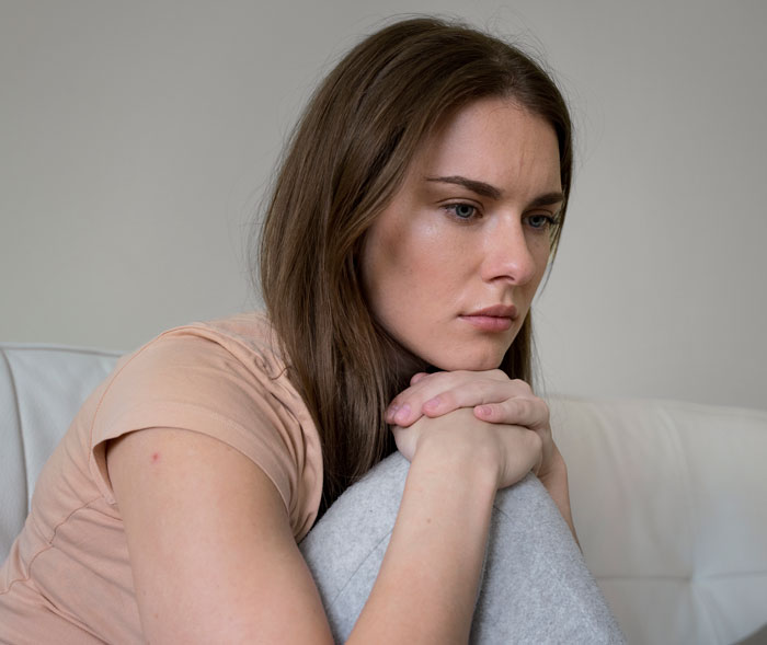 Young woman with serious expression sitting on couch, reflecting on weight loss medication prescribed by doctor. Young woman with serious expression sitting on couch, reflecting on weight loss medication prescribed by doctor.
