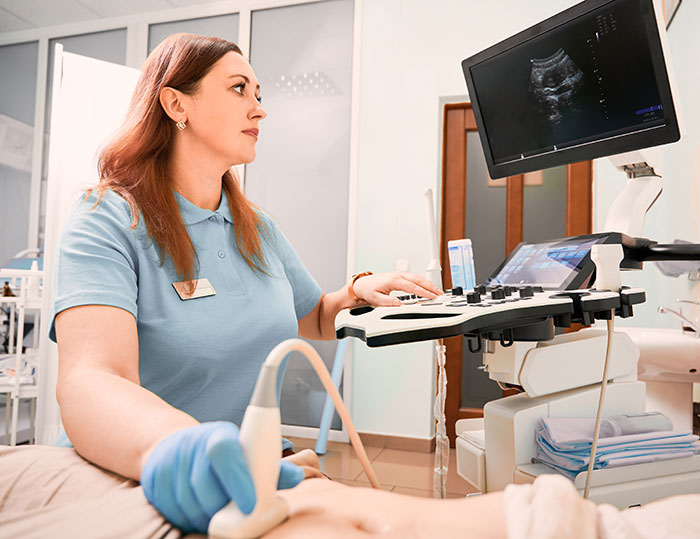 Ultrasound technician performing a scan while monitoring baby gender details potentially spoiled during the session.