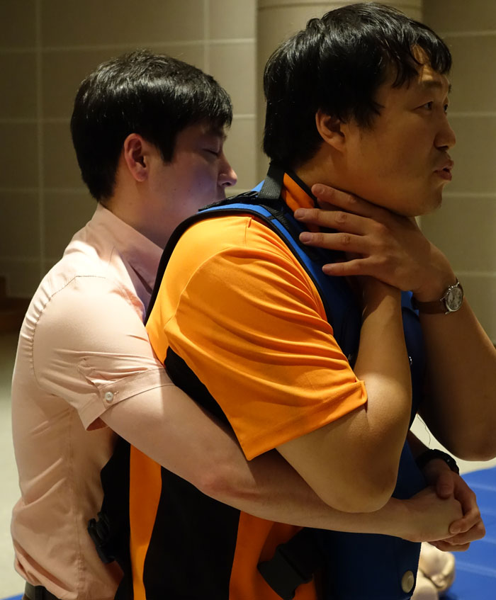 Two men demonstrating a safety technique for choking rescue, illustrating tips to stay safe and alive.