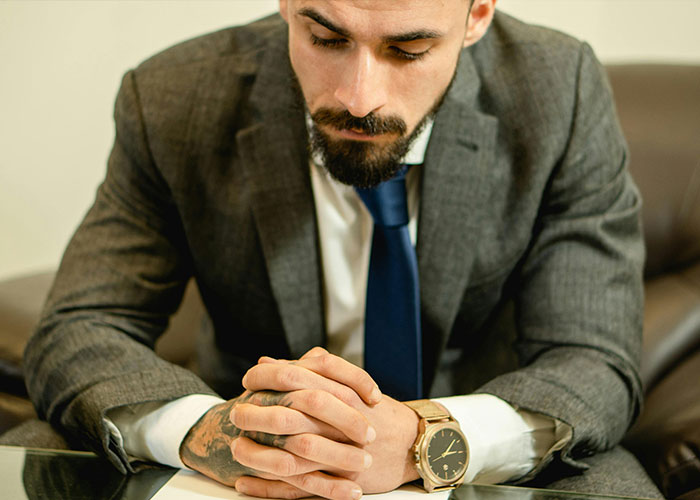 Man in suit sitting at a desk looking down thoughtfully, reflecting on worst cheating stories and their impact.