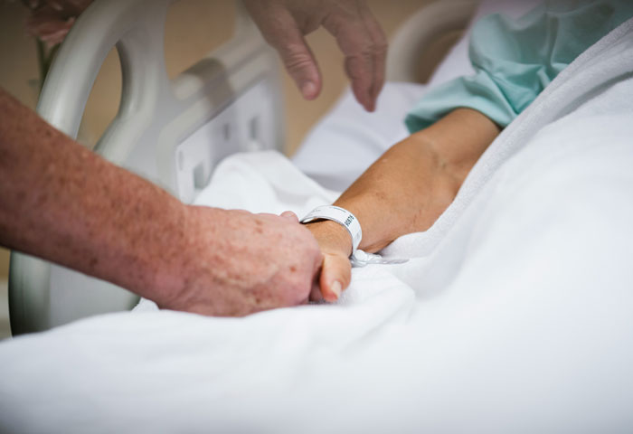 Hands of support group member holding wrist of woman in hospital bed after she ended her own life by starving. - 4