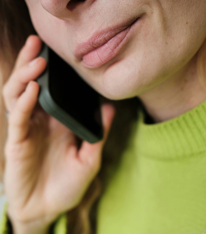 Close-up of a person in a green sweater speaking on a phone, highlighting concerns about medical professionals and patient privacy. - 2
