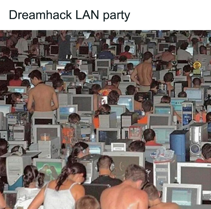 Large group of people at a Dreamhack LAN party surrounded by old computer monitors and retro technology.