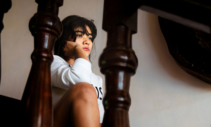 Young girl sitting thoughtfully indoors, reflecting on a makeup moment shared between aunt and niece. - 4