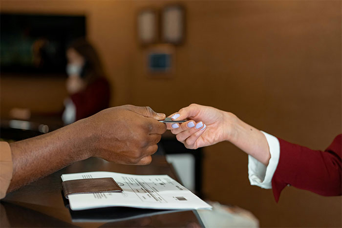 Guest at hotel front desk handing card to staff member, illustrating hotel pool access after closure situation. - 13