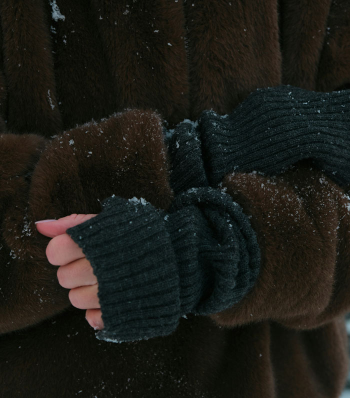 Close-up of hands in dark gloves and brown coat with snowflakes, illustrating tips to stay safe and alive in cold weather.