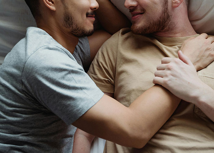 Two men lying close together in an intimate embrace, illustrating themes of love and cheating stories.