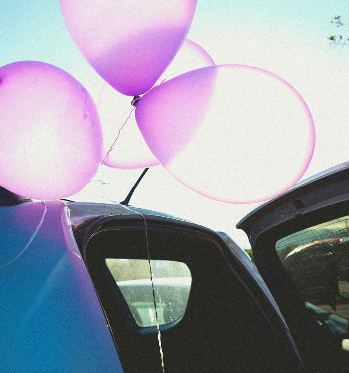 Pink balloons tied to a car door at a wedding, symbolizing moments people regretted accepting a wedding invitation. - 40