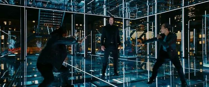 Three men in dark clothing engage in a fight inside a mirrored room, illustrating common worst movie tropes.
