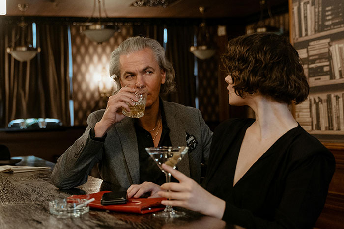 A man and woman having drinks at a bar with dim lighting, illustrating social interaction and microfeminism themes.