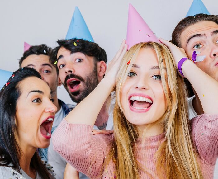 Group of young adults celebrating with party hats, expressing surprise and joy related to outrageous student names.