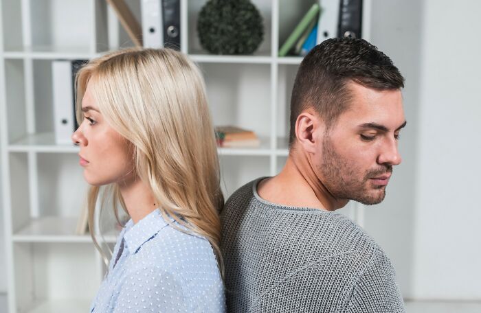 Young couple sitting back to back looking upset, illustrating signs a couple’s days might be numbered.