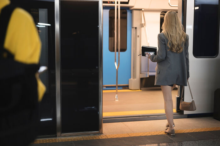 Woman wearing blazer and sandals walking onto a subway train, illustrating things people really did in public spaces.