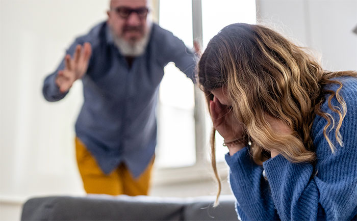 Woman upset and covering face while dad gestures in frustration in a tense moment after last attempt to share important news.