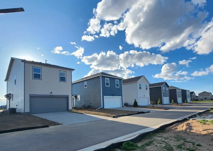 Row of modern suburban homes with smooth driveways under a bright sky, showcasing unique home design fails.