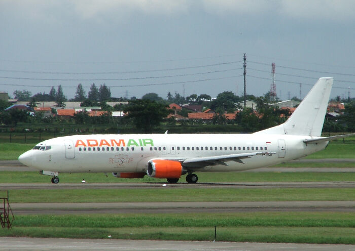 Adam Air commercial airplane on runway with visible engines and clear skies, related to pilots and plane crash keywords.
