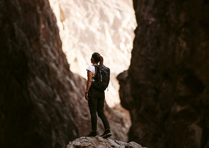 Hiker standing on rocky terrain between cliffs, illustrating tips to stay safe and alive in outdoor adventures.