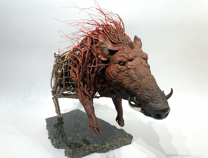 Striking scrap metal animal sculpture of a running boar with detailed metalwork and textured mane on stone base.