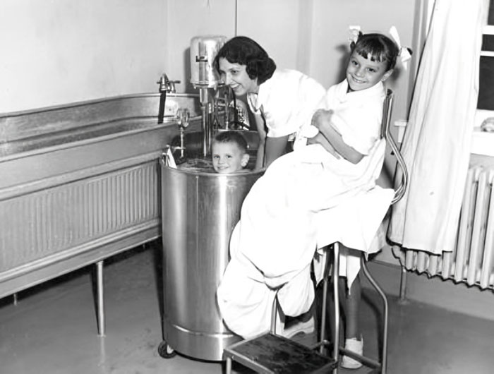 Child receiving treatment in an old medical device with nurse assistance, illustrating unsettling medical devices from the past.
