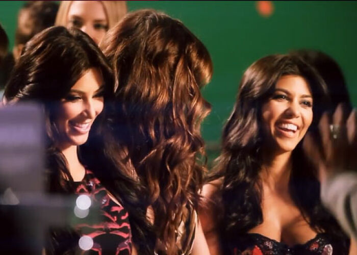 Three women from the KarJenner clan smiling and interacting with each other in a lively event setting. - 23