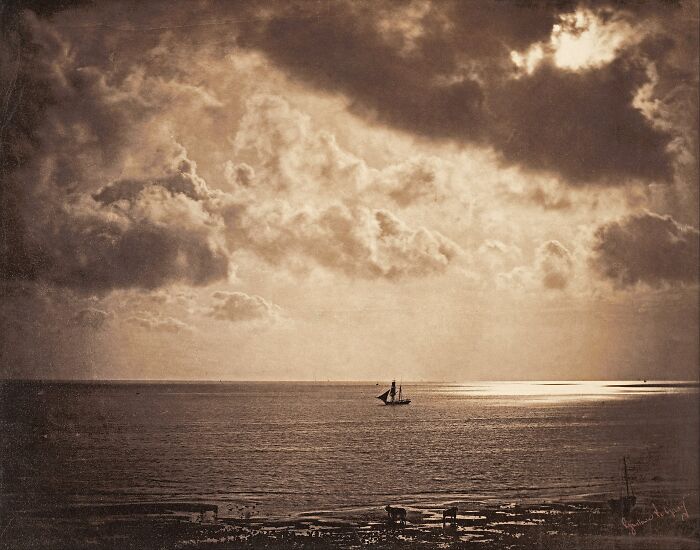 19th century photo capturing a sailboat on calm waters under dramatic clouds, showcasing invaluable historic imagery.