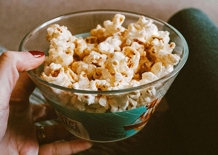 Person holding a bowl of popcorn reflecting bizarre family habits people thought were completely normal.