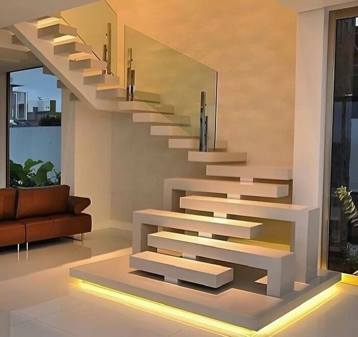 Modern creative home staircase design with floating steps and glass railing in a minimalist living room setting.